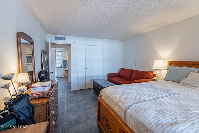bedroom featuring a textured ceiling, visible vents, and a closet