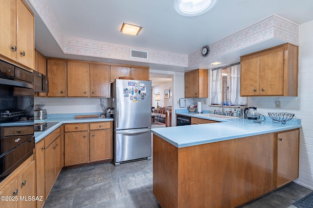 kitchen with visible vents, brown cabinetry, light countertops, a sink, and black appliances