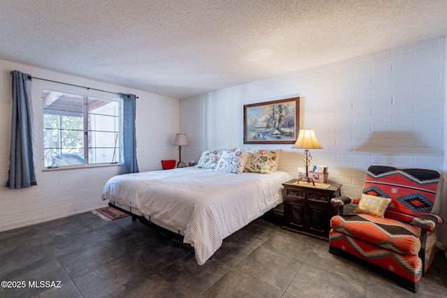 bedroom with concrete block wall and a textured ceiling