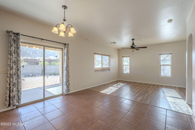 tiled spare room with baseboards and ceiling fan with notable chandelier