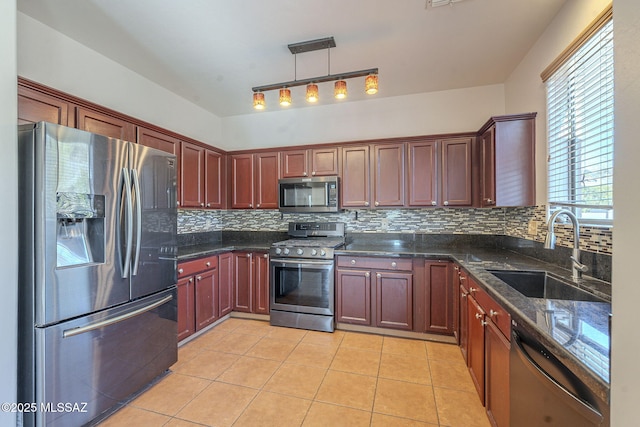 kitchen with light tile patterned flooring, dark stone counters, a sink, backsplash, and stainless steel appliances