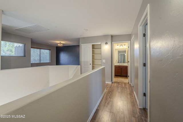corridor with baseboards, hardwood / wood-style flooring, and visible vents