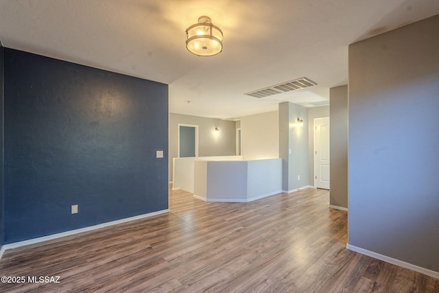 empty room featuring visible vents, baseboards, and wood finished floors
