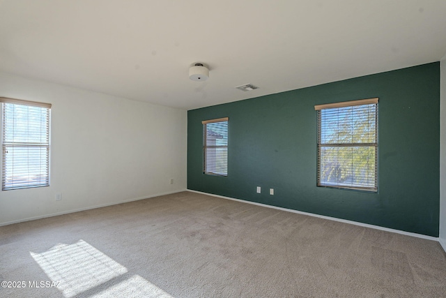 carpeted empty room featuring baseboards and visible vents