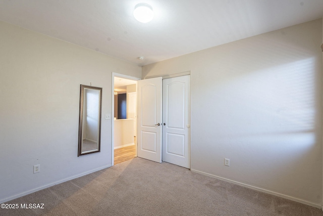 unfurnished bedroom featuring baseboards, carpet, and a closet