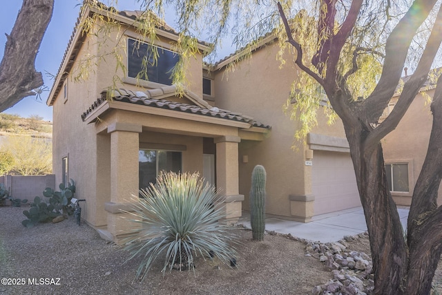 view of front of house with stucco siding, an attached garage, and a tiled roof