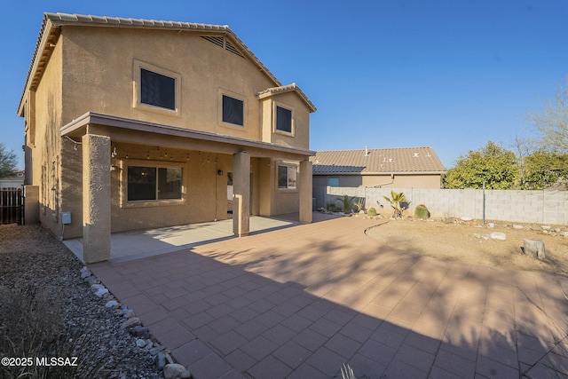 rear view of house with a patio, a fenced backyard, and stucco siding