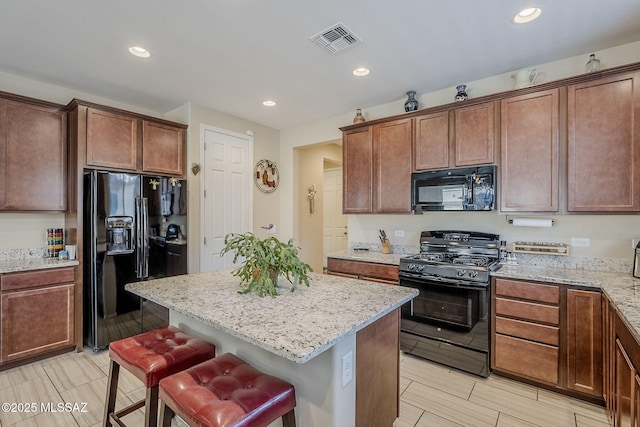 15726 S Camino Oculi, Sahuarita, AZ 85629 - kitchen with light stone countertops, visible vents, black appliances, and a center island