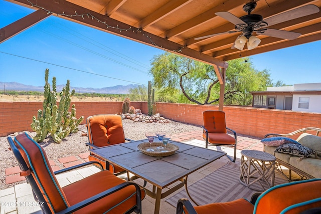 view of patio featuring a fenced backyard, a mountain view, ceiling fan, and outdoor dining space