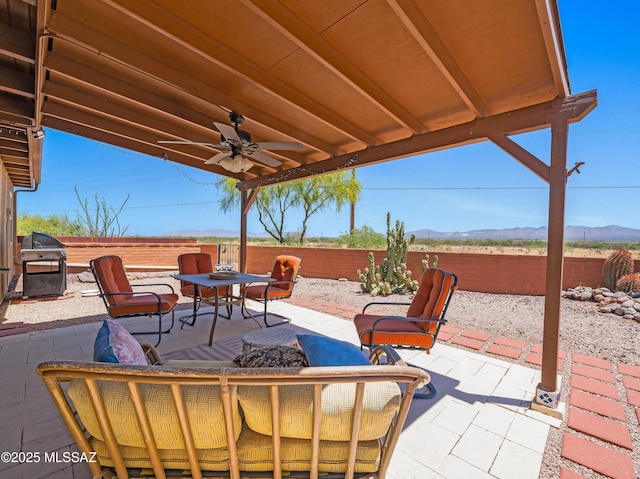 view of patio featuring ceiling fan, a grill, outdoor dining area, a fenced backyard, and a mountain view