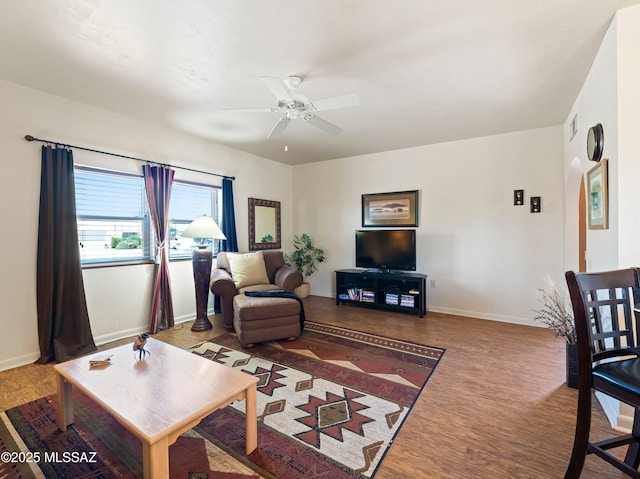living room featuring a ceiling fan, baseboards, and wood finished floors