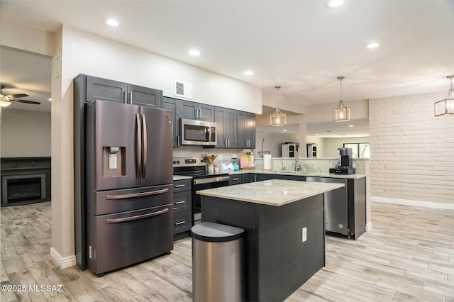 kitchen with stainless steel appliances, visible vents, light wood finished floors, and a peninsula