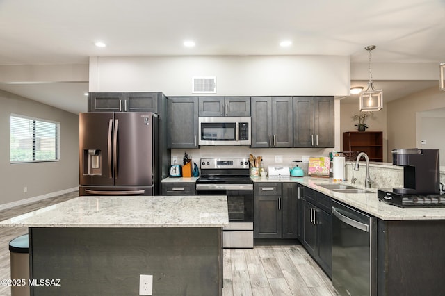 kitchen with visible vents, a sink, a peninsula, light wood-style floors, and stainless steel appliances