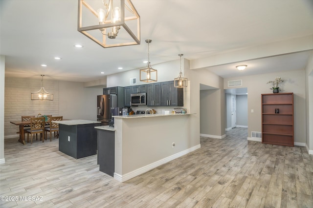 kitchen with light countertops, light wood-style floors, stainless steel appliances, and a chandelier