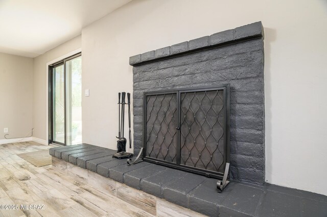 room details featuring baseboards, a fireplace, and wood finished floors