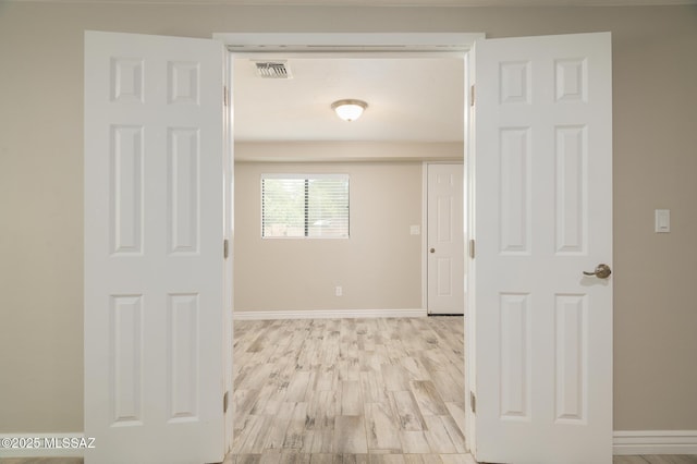 hallway featuring baseboards, visible vents, and light wood-style floors