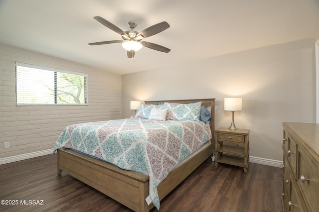 bedroom featuring a ceiling fan, baseboards, dark wood finished floors, and brick wall