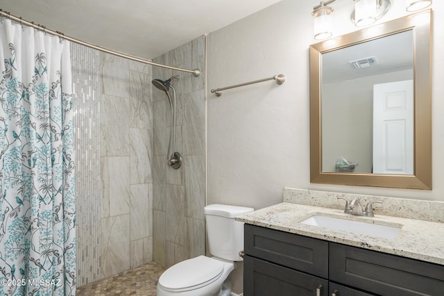 full bathroom with vanity, a tile shower, toilet, and visible vents