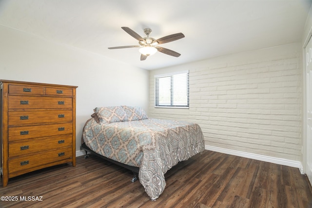 bedroom featuring a ceiling fan, baseboards, dark wood-type flooring, and brick wall