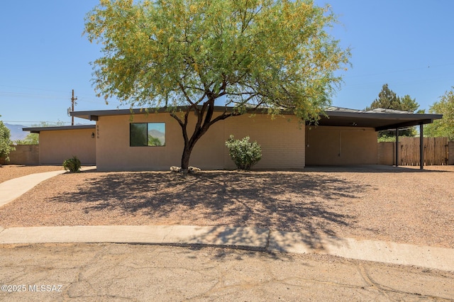 ranch-style house with stucco siding, fence, driveway, and a carport