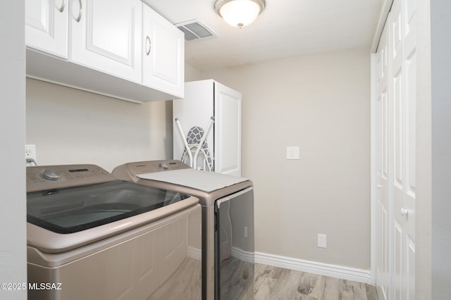 washroom with visible vents, baseboards, cabinet space, separate washer and dryer, and light wood-style flooring