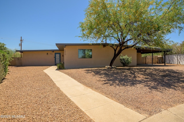 ranch-style home featuring fence and stucco siding