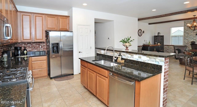 kitchen featuring appliances with stainless steel finishes, a sink, dark stone countertops, light tile patterned floors, and backsplash