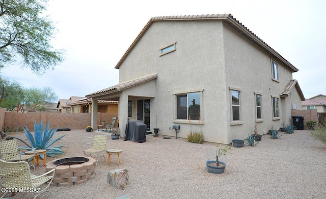 rear view of property with a tile roof, a fenced backyard, an outdoor fire pit, a patio, and stucco siding