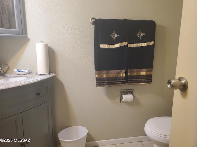 bathroom featuring vanity, baseboards, tile patterned floors, and toilet
