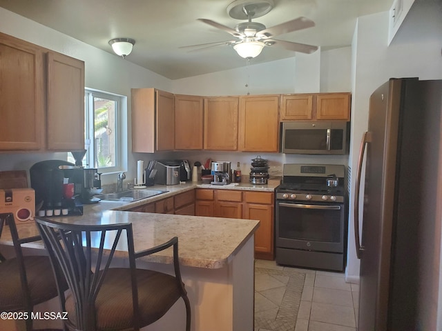 kitchen featuring a peninsula, lofted ceiling, light countertops, a sink, and stainless steel appliances