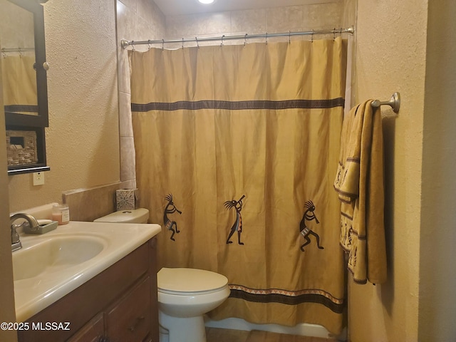 bathroom featuring vanity, a textured wall, a shower with curtain, and toilet