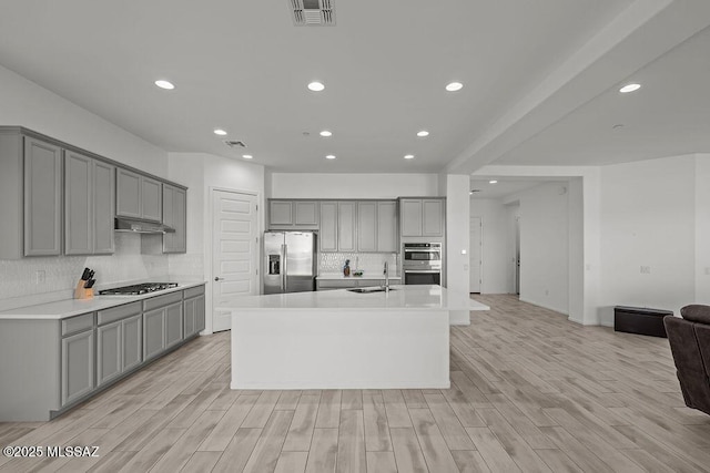 kitchen featuring visible vents, open floor plan, gray cabinets, tasteful backsplash, and stainless steel appliances