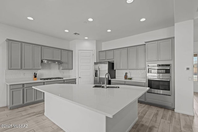 kitchen with visible vents, a sink, gray cabinets, and light wood finished floors