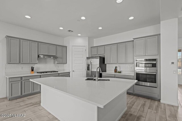 7956 S Desert Indigo Dr, Tucson, AZ 85747 - kitchen with gray cabinets, stainless steel appliances, light wood-style floors, decorative backsplash, and recessed lighting