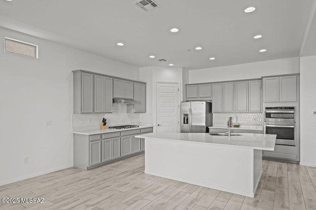 kitchen featuring a sink, appliances with stainless steel finishes, gray cabinets, and visible vents