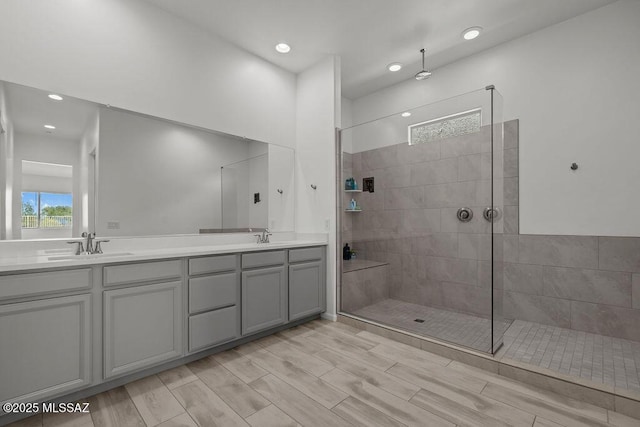 bathroom with a sink, a walk in shower, recessed lighting, and double vanity
