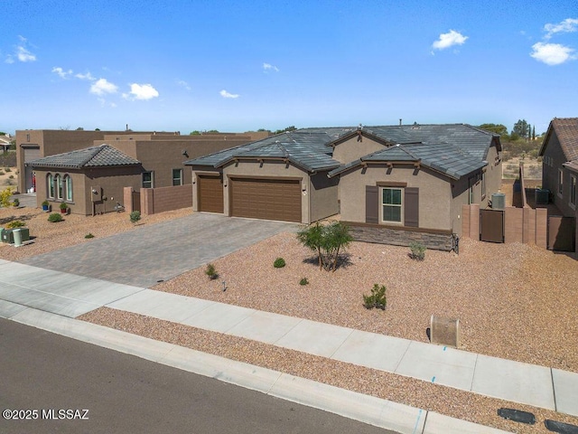view of front of house with fence, stucco siding, a gate, an attached garage, and driveway