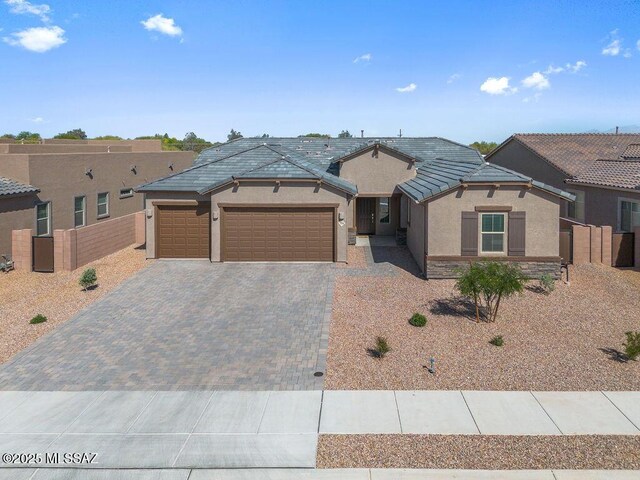 7956 S Desert Indigo Dr, Tucson, AZ 85747 - view of front of property with stucco siding, driveway, an attached garage, a gate, and roof mounted solar panels