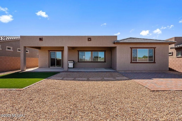 rear view of house with fence, stucco siding, and a patio area