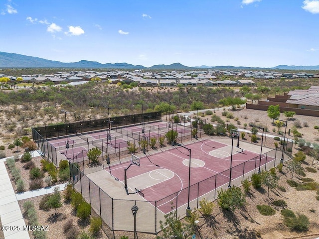 view of sport court featuring community basketball court, fence, a residential view, and a mountain view