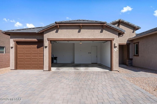 ranch-style house with an attached garage, stucco siding, and decorative driveway