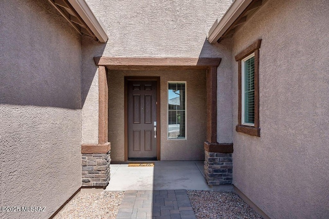 entrance to property with stucco siding and stone siding