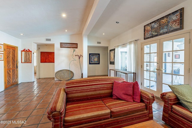 living area with tile patterned floors, visible vents, french doors, and lofted ceiling