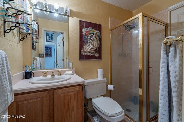 bathroom featuring vanity, a textured wall, and a stall shower