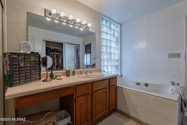 full bathroom with vanity, tile patterned floors, a textured wall, and a bath