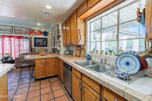 kitchen featuring stainless steel dishwasher, visible vents, a peninsula, a healthy amount of sunlight, and a sink