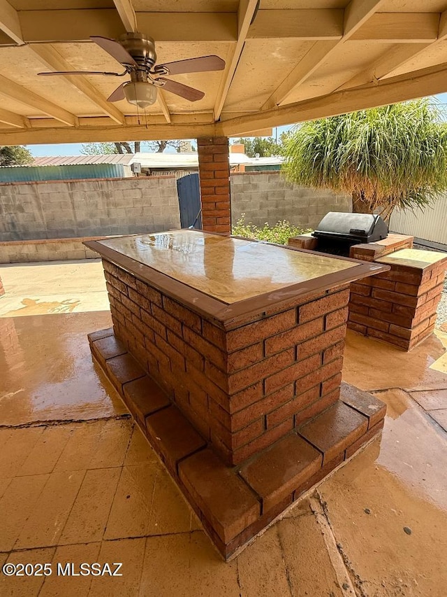 view of patio featuring a fenced backyard, ceiling fan, exterior kitchen, and area for grilling