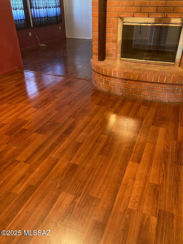 details with a brick fireplace and wood finished floors