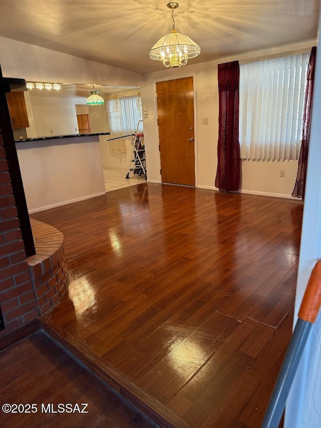 interior space with baseboards, an inviting chandelier, and wood finished floors