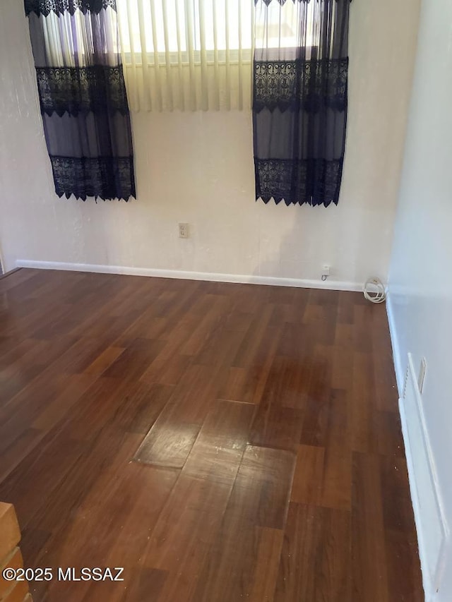 unfurnished room with baseboards and wood finished floors